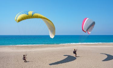 Skydivers landing on the beach.