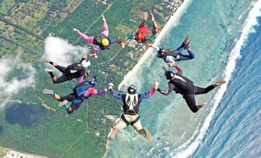 An aerial view of friends holding hands while jumping from a plane in a skydiving experience.