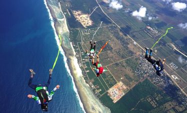 An aerial view of friends jumping from a plane in a skydiving experience.