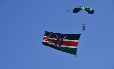 A person skydiving holding the flag of Kenya.